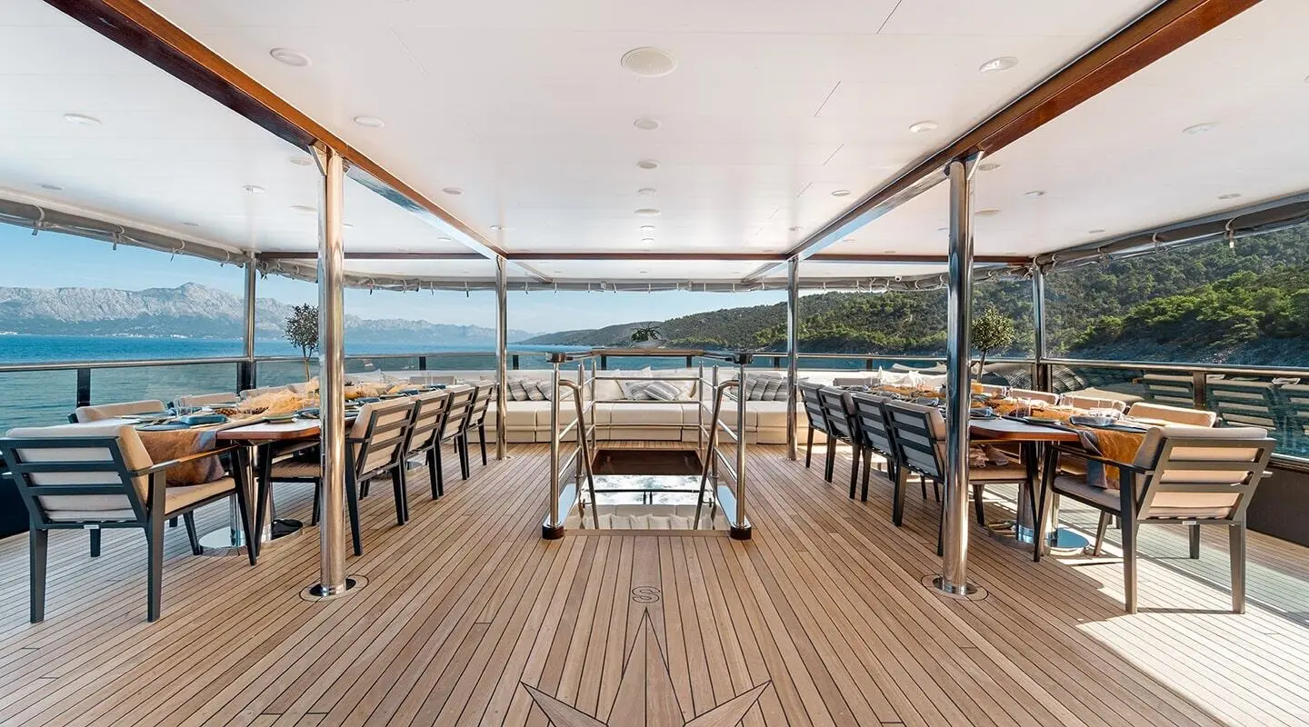 Dining on a yacht deck at sunset, chairs around a table with ocean view