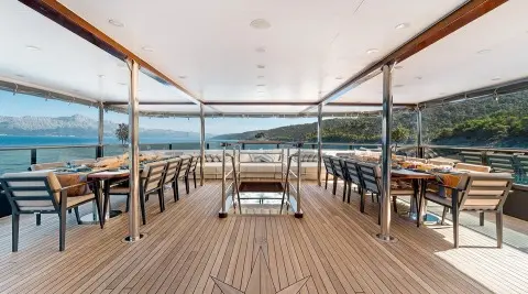 Dining on a yacht deck at sunset, chairs around a table with ocean view