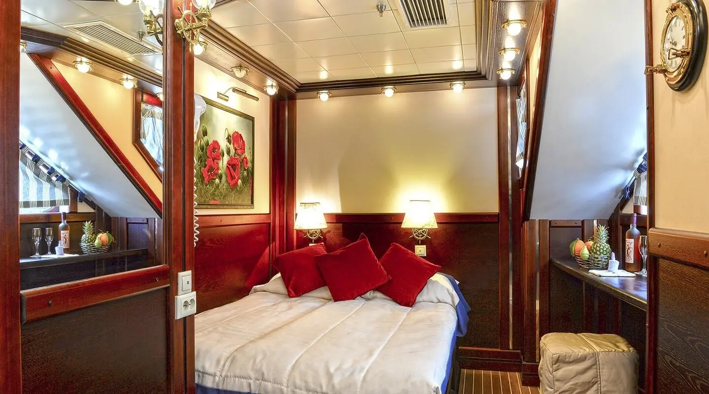 Interior cabin on a gulet, bed with red pillows and wooden panels