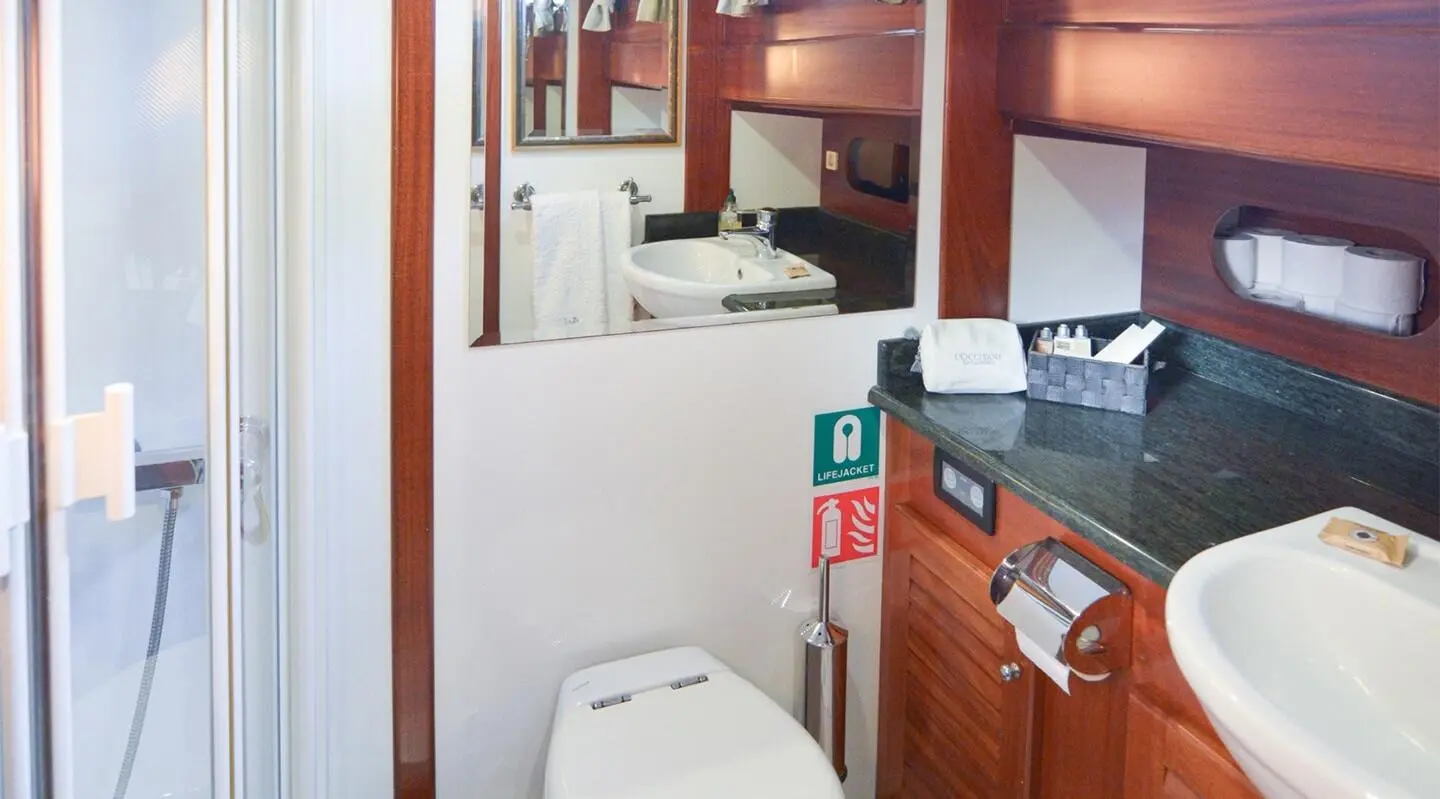 Interior of a yacht bathroom on Ros Mare, wood cabinetry and white fixtures