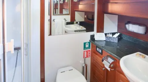 Interior of a yacht bathroom on Ros Mare, wood cabinetry and white fixtures