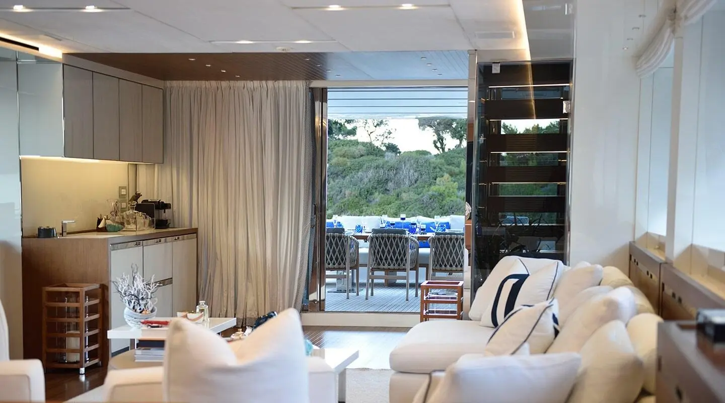 Living room with door to outdoor deck and dining area on the yacht