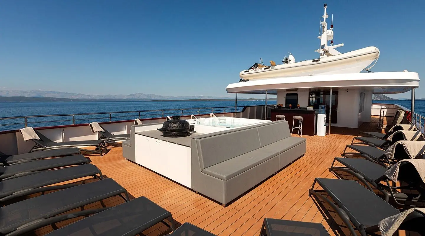 Open yacht deck with lounge seating and a hot tub on a sunny day