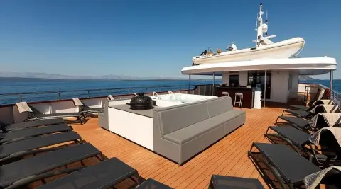 Open yacht deck with lounge seating and a hot tub on a sunny day
