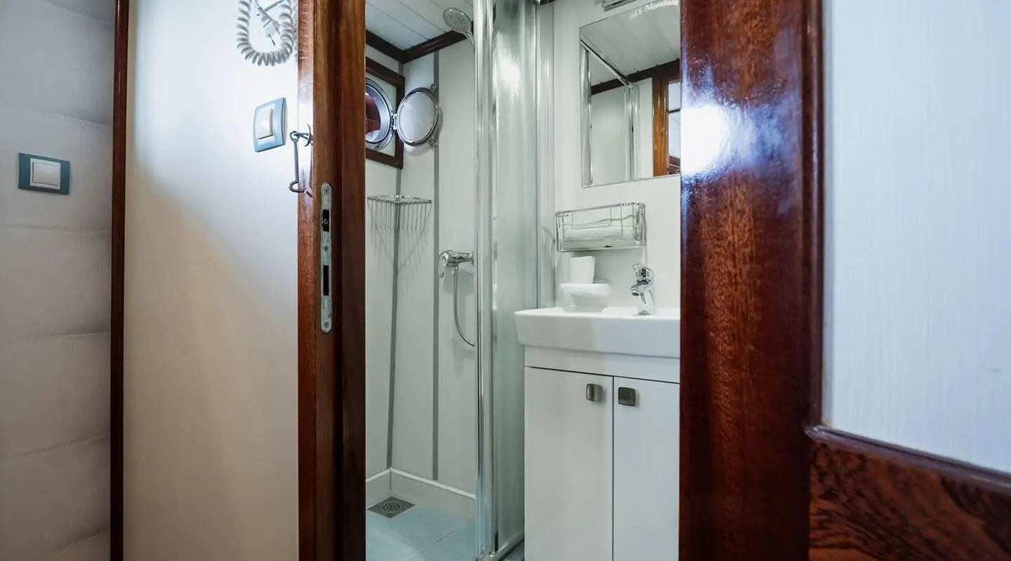 Mendula yacht cabin shower and sink area with white cabinetry and chrome fixtures