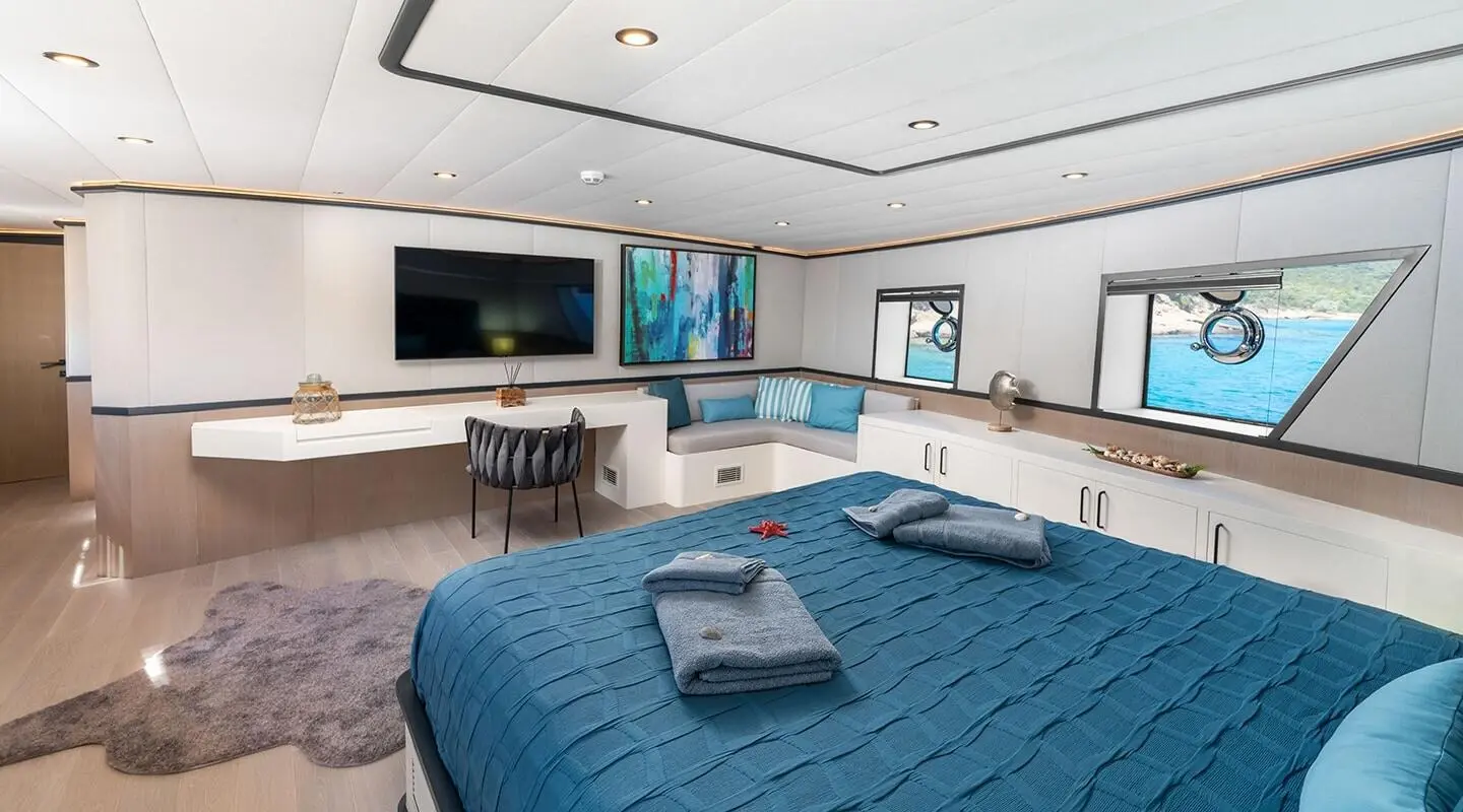 Calm Down yacht master cabin with blue bedspreads and seating area