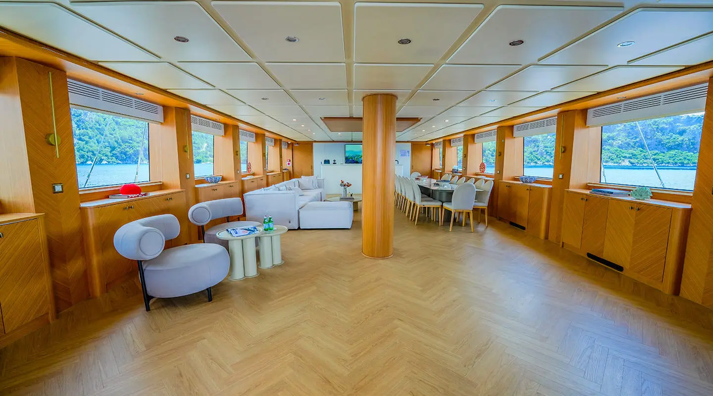 Spacious yacht saloon with wooden floor, seating, and large windows