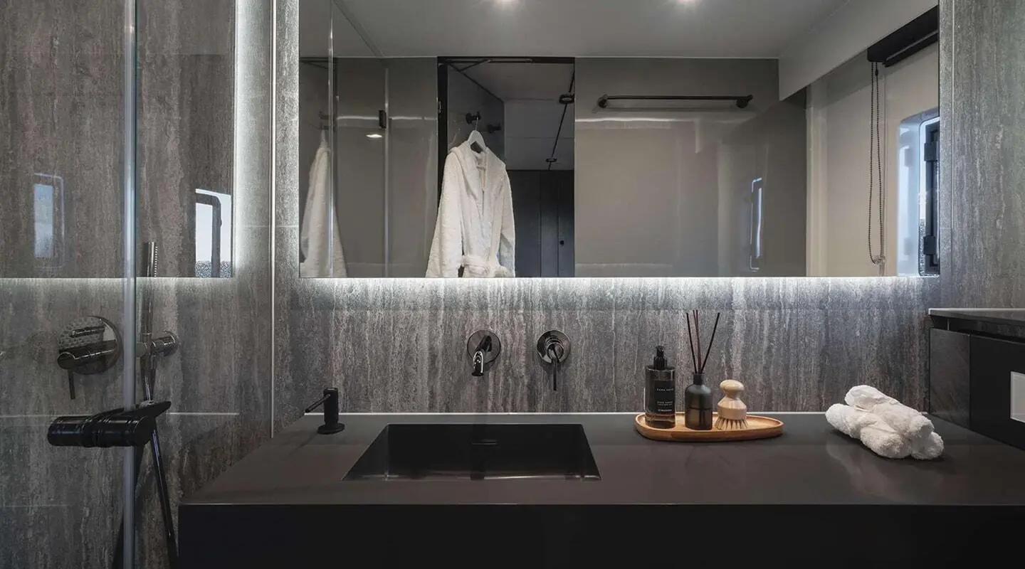 Alteya yacht bathroom with sleek dark vanity, mirror, and bottled amenities