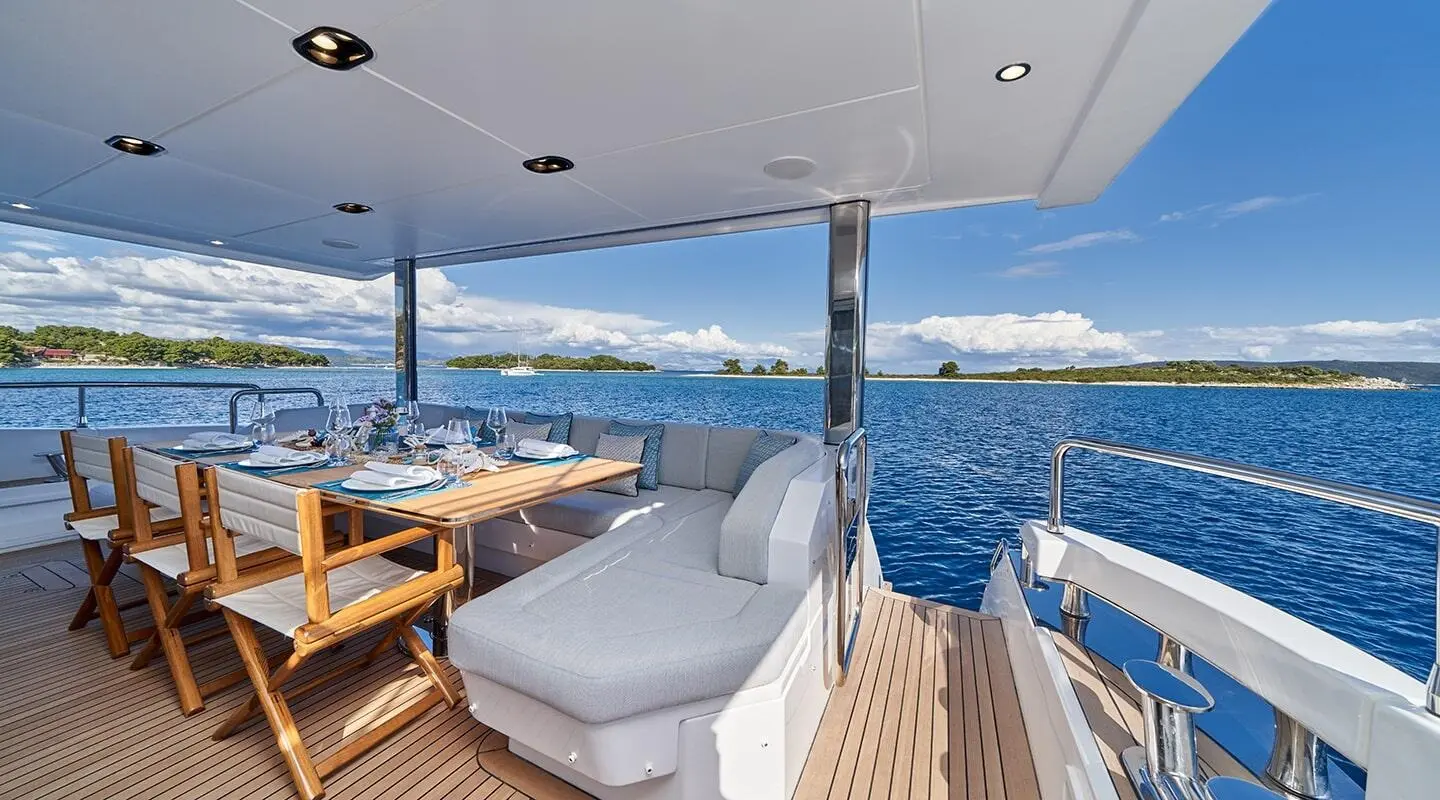 Luxurious yacht Aluminia Too deck with seating, dining area, and blue ocean view at sunset