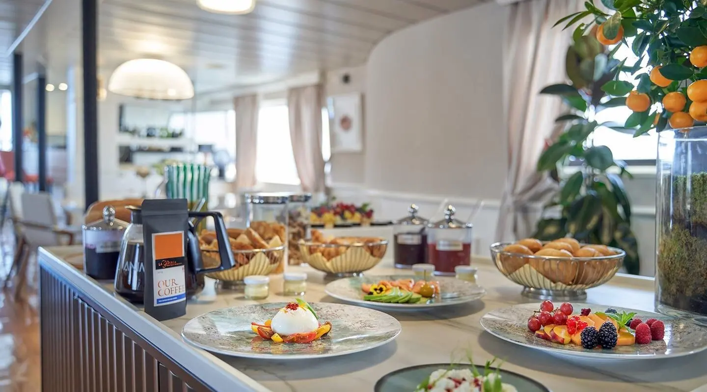La Perla yacht onboard dining deck with plates, fruit and beverages set upscale
