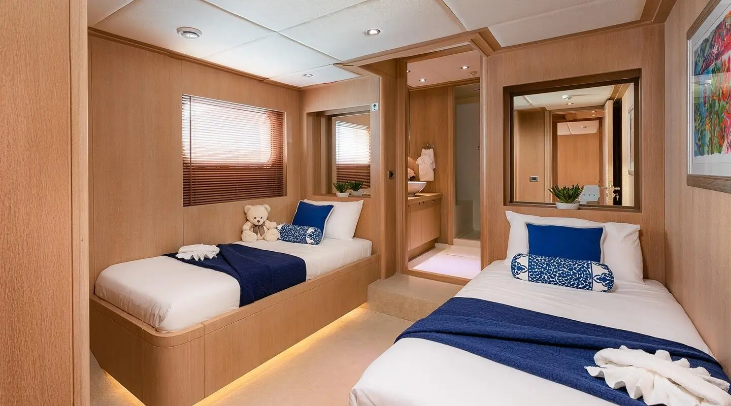 Grace yacht interior with two blue and white beds and wood furnishings