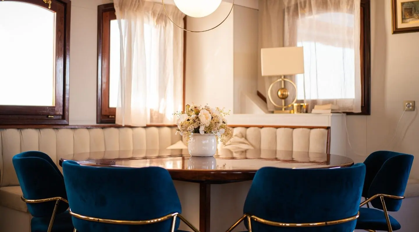 Interior salon on Bellezza yacht with cream seating, draped curtains, and glass table