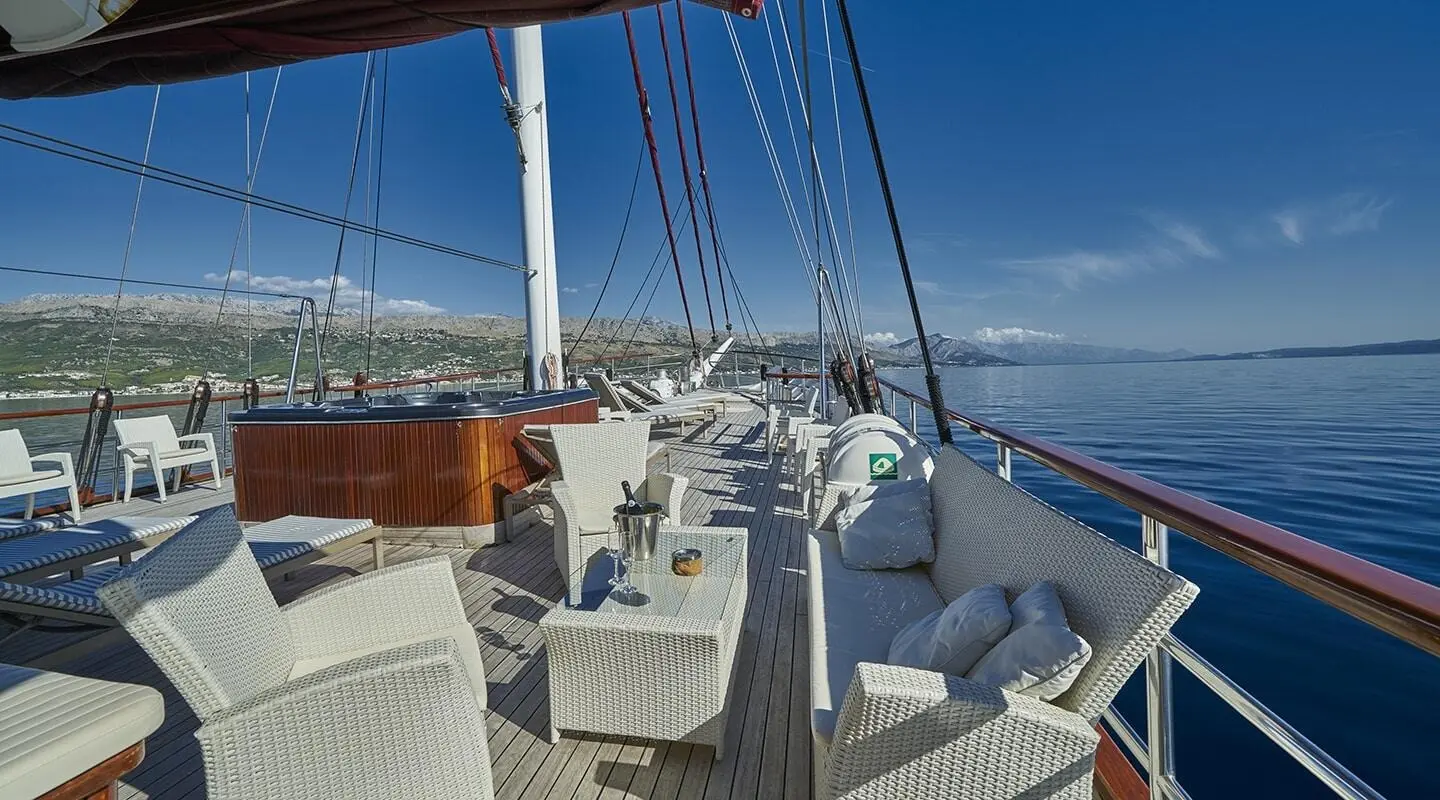 Amorena motor yacht upper deck with seating, helm, and blue ocean view