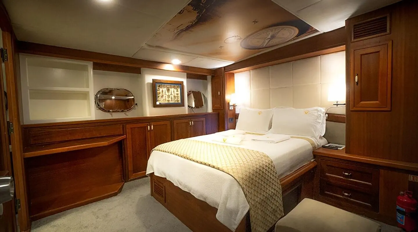 A luxury yacht Virtuoso bedroom with twin beds, wood accents, and warm lighting