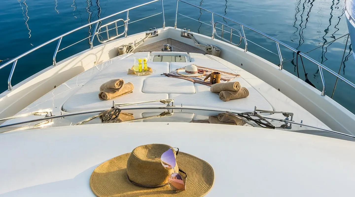 Top deck of Amoraki yacht with sun loungers and a hat on a circular deck