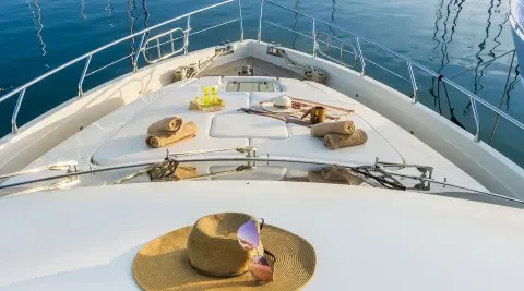 Top deck of Amoraki yacht with sun loungers and a hat on a circular deck
