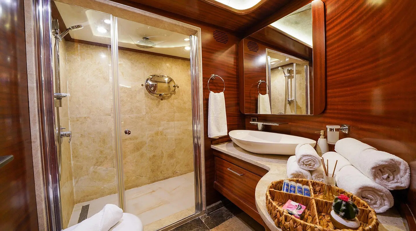 La Bella Vita yacht interior: wooden ceiling beams, tiled bathroom, towels, and glass shower door