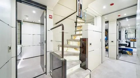 Interior staircase on a luxury motor yacht, white walls and glass panels