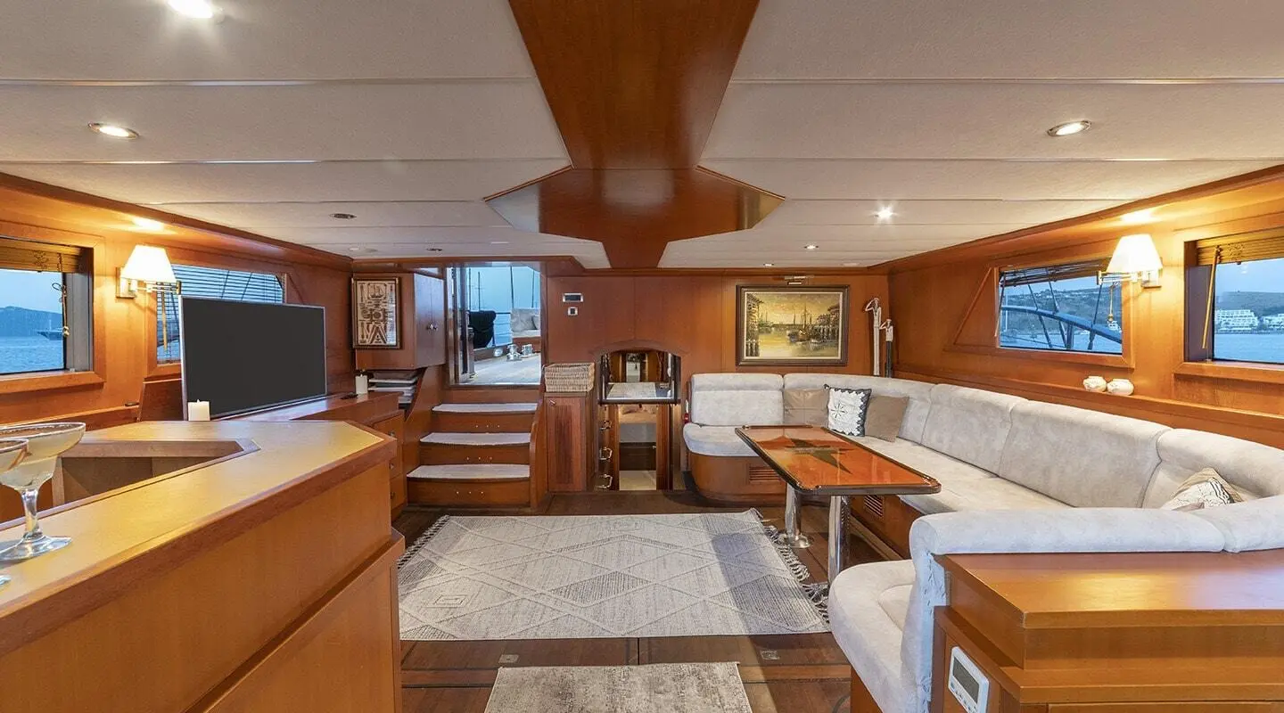 Arabella yacht interior with wood panels, seating, and dining area at sunset