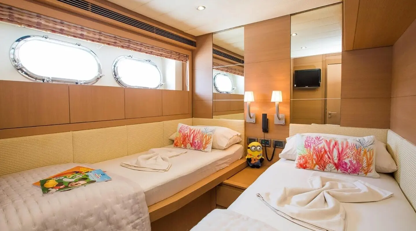 Salt yacht twin cabin interior with porthole windows and coral-themed pillows