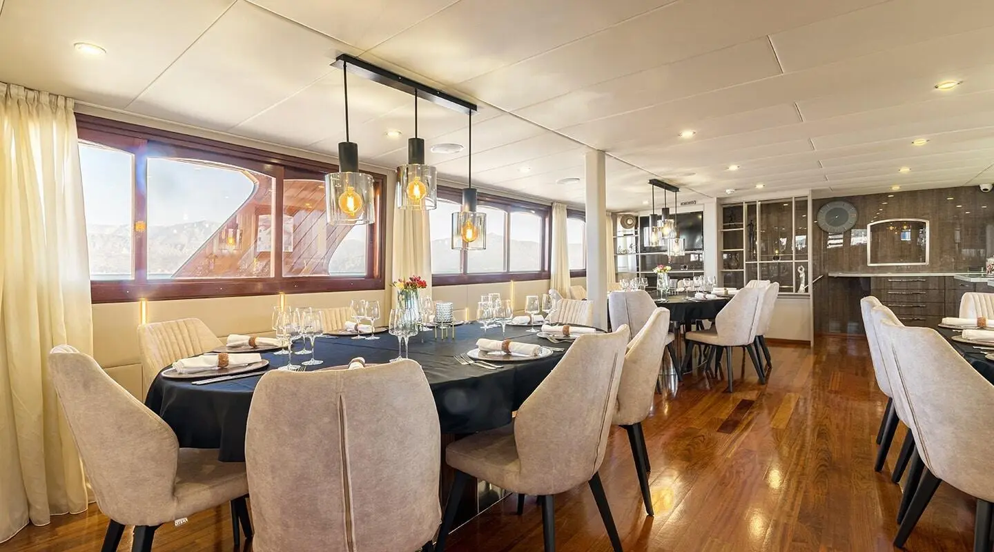 Yacht Melody saloon interior with beige chairs, wooden accents, and large windows