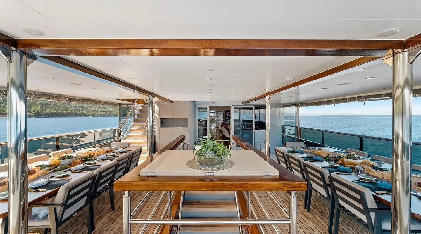 Freedom yacht dining table set on deck under a shaded awning during sunset