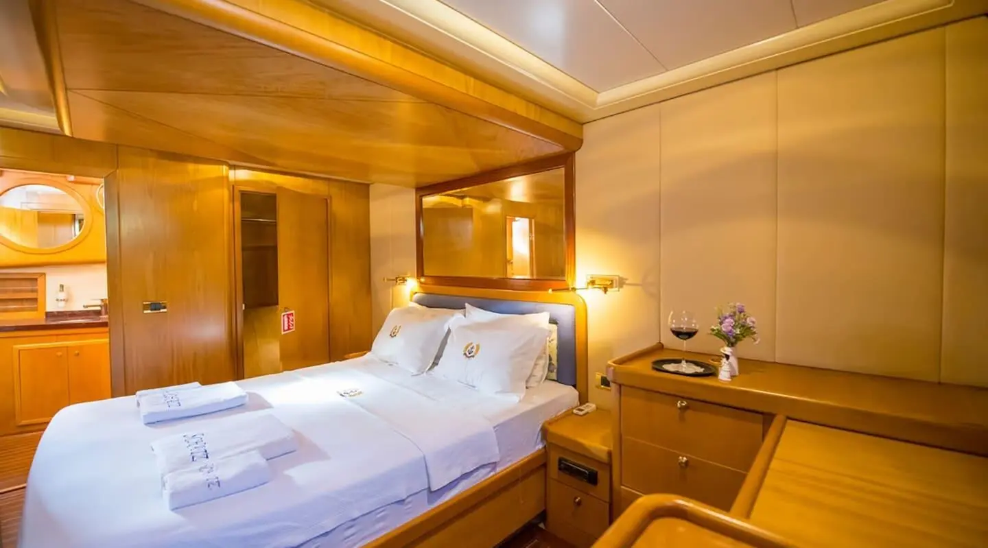 Cozy yacht bedroom with white bedding, wooden accents, and warm lighting