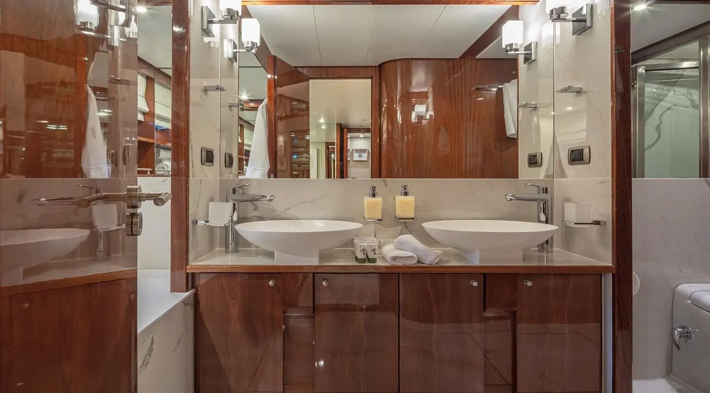 Grace yacht bathroom with wood cabinets, mirror, and sink cluttered with items