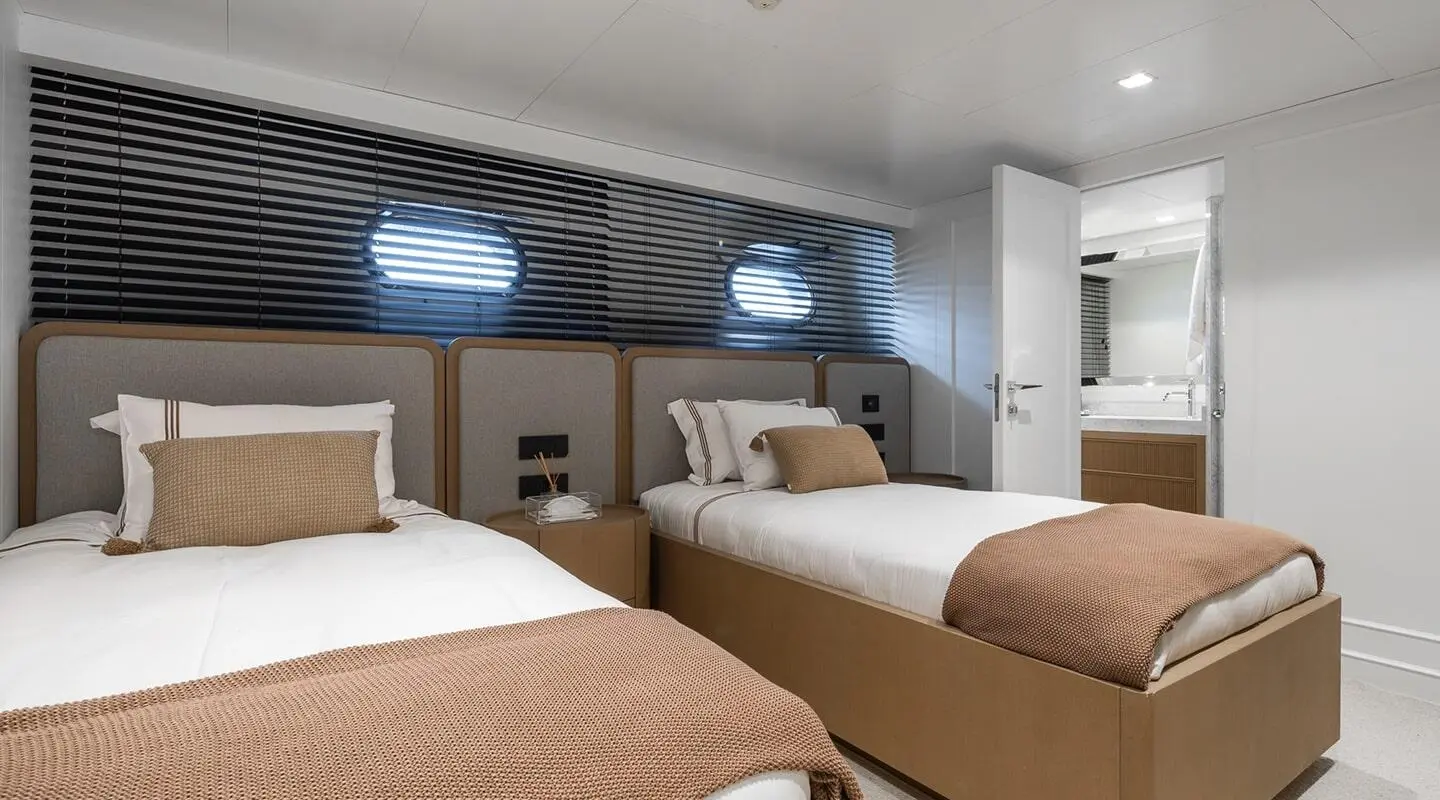 Illusion II yacht interior with two twin beds, brown bedspreads, wall panels, and bedside lamps
