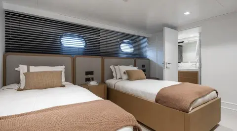 Illusion II yacht interior with two twin beds, brown bedspreads, wall panels, and bedside lamps