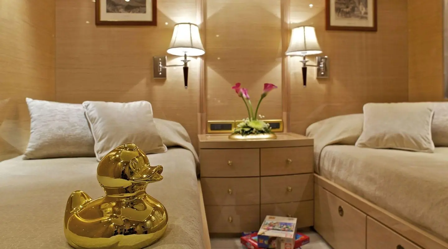 Two neatly made beds with wooden headboards, twin lamps, and a bedside table between them