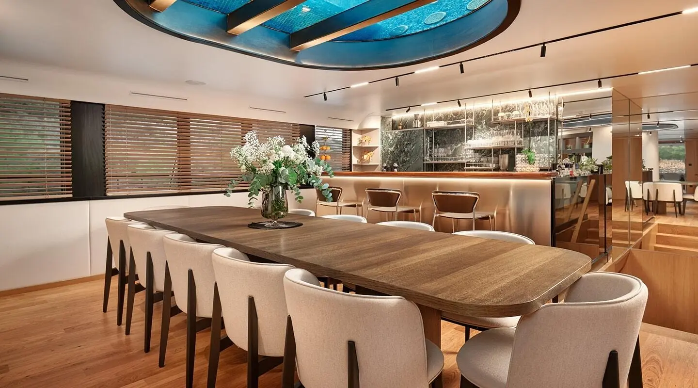 Anetta yacht dining room with long wooden table and white upholstered chairs
