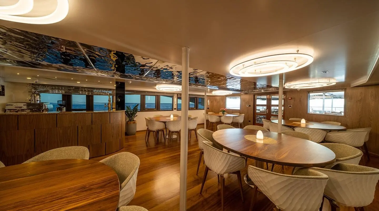 Interior view of a yacht salon with wooden panels, seating, and round table