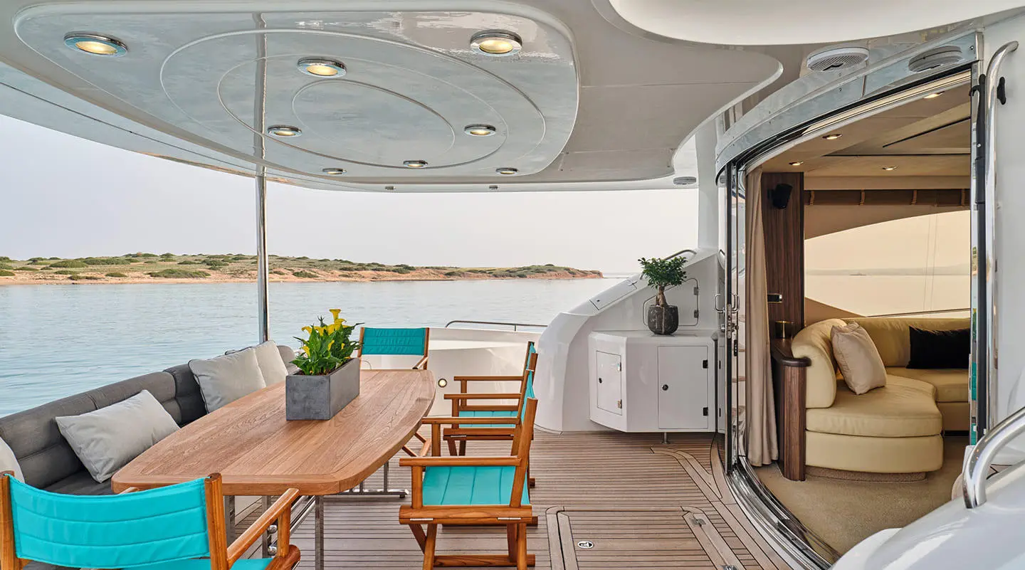 Deck seating area on M Five yacht with wooden table, benches, and potted plant