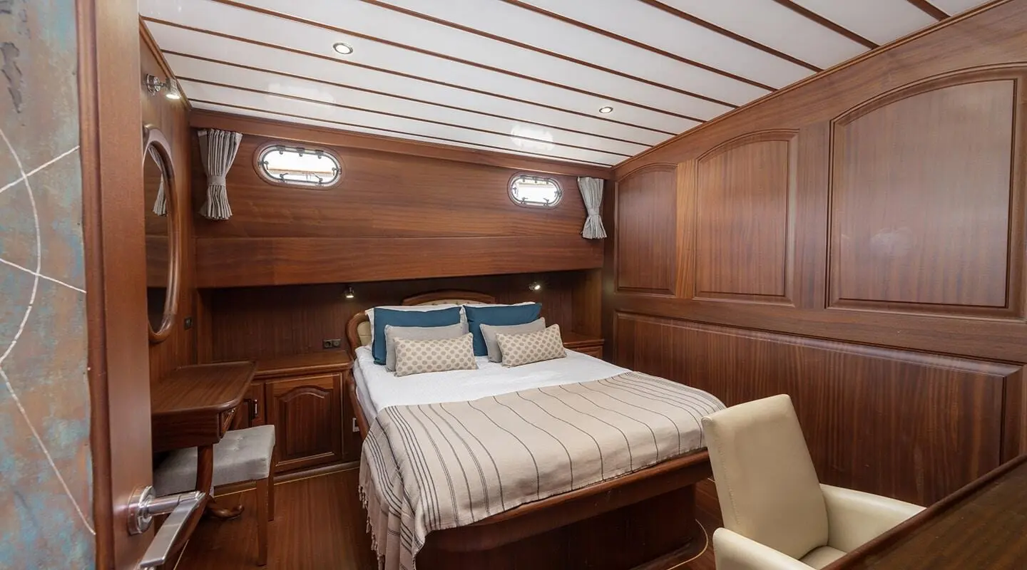 Interior cabin on Bedia Sultan gulet with double bed, wooden panels, blue and white bedding