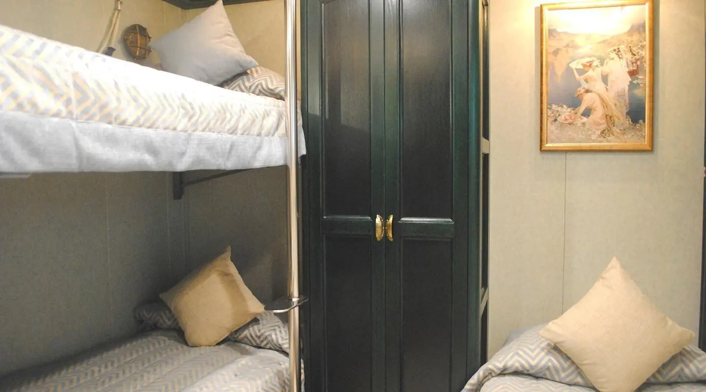 Interior cabin with green wardrobe between bunk beds and overhead storage