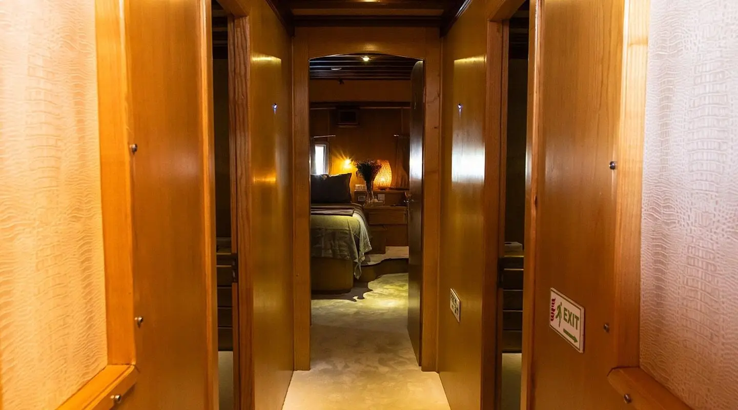 Interior corridor of a yacht with wooden walls, warm lighting, and a distant cabin