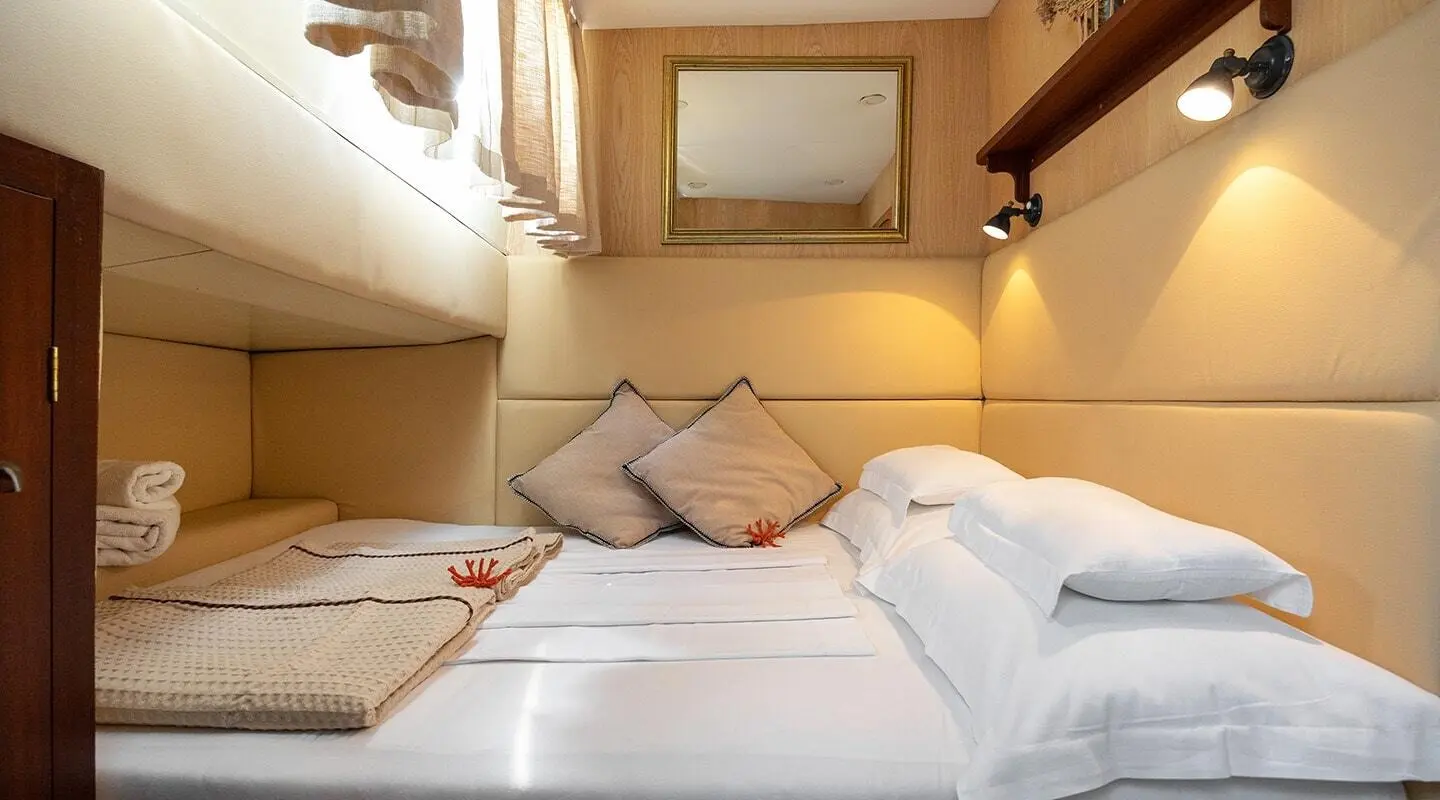 Cozy yacht cabin with two single beds arranged as a bed, pillows, and warm lighting