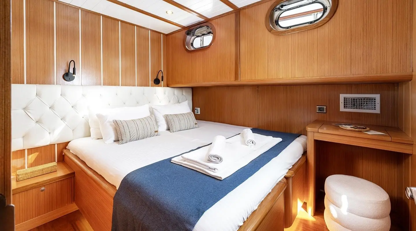 Interior of gulet Gozdem The One with double cabin, wood paneling, bed, and folded towel