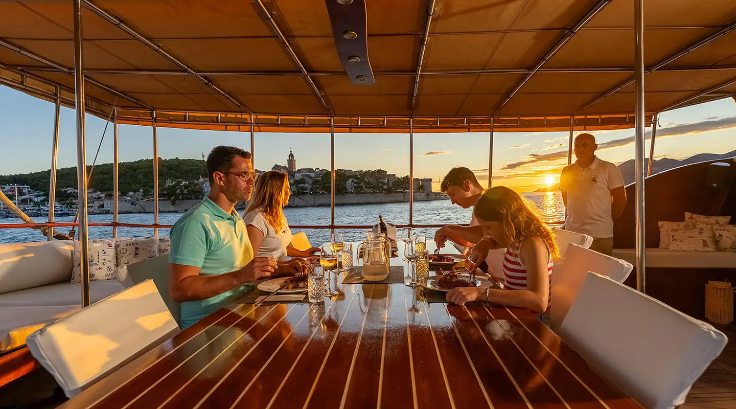 Gulet Eleganza at sunset with diners on deck and glasses on table