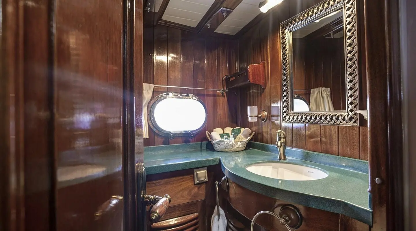 Interior view of a luxurious yacht with wood paneling, round window, and blue-tinted tub area