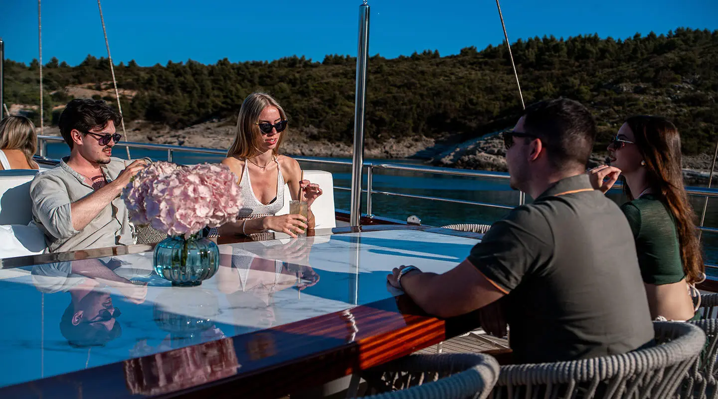 Nocturno yacht sun deck with people seated by a table on a clear day