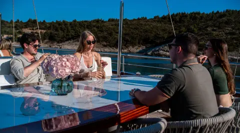 Nocturno yacht sun deck with people seated by a table on a clear day