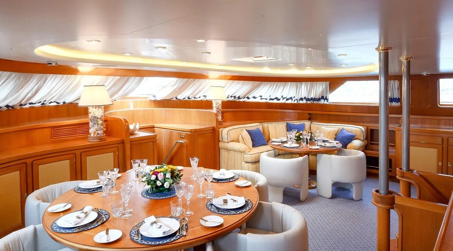 Interior dining area on Tamarita yacht with wooden table settings and seating