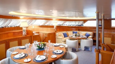 Interior dining area on Tamarita yacht with wooden table settings and seating