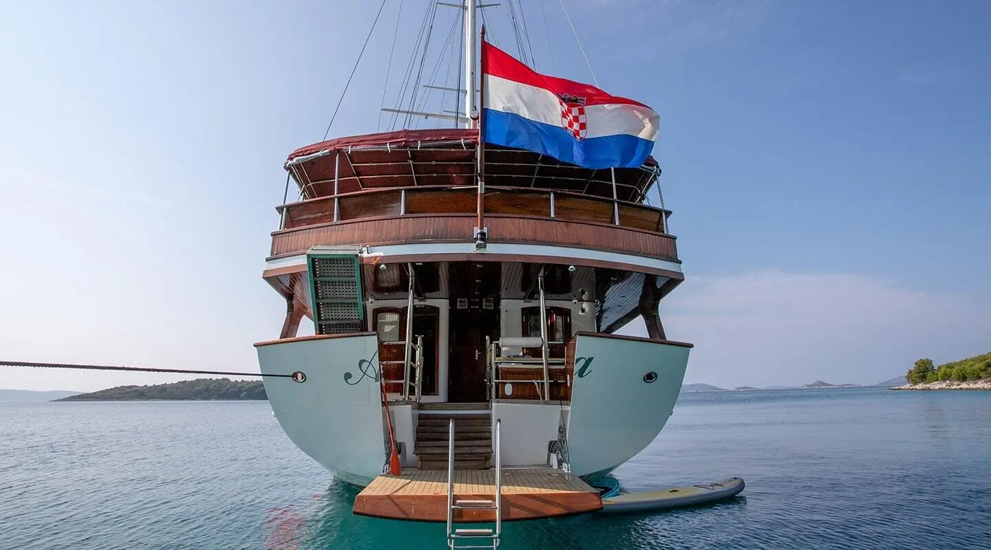 Amorena yacht at anchor with stern view, flag fluttering in breeze