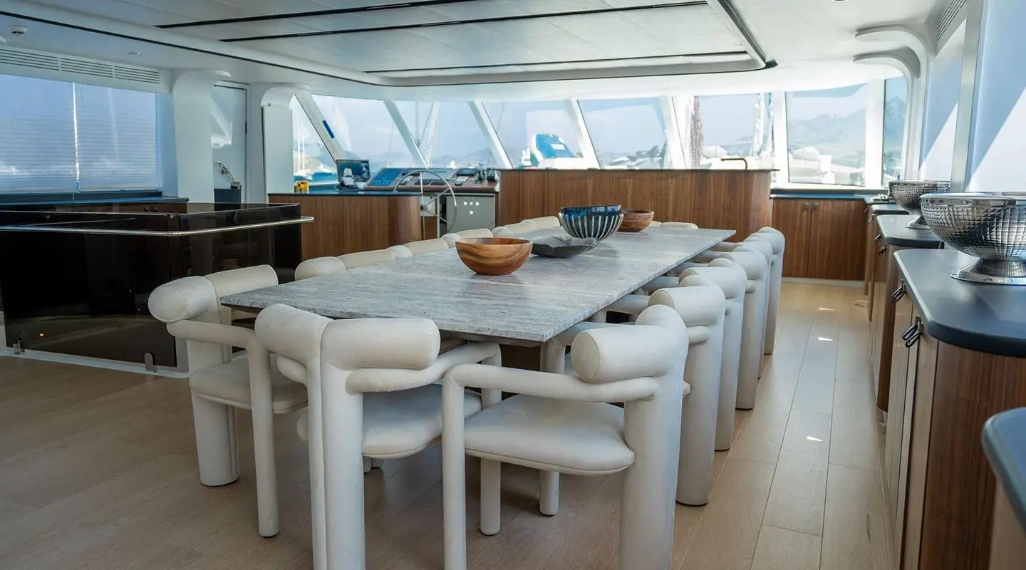 Deck dining area on De Love yacht with long white tables and cushioned benches