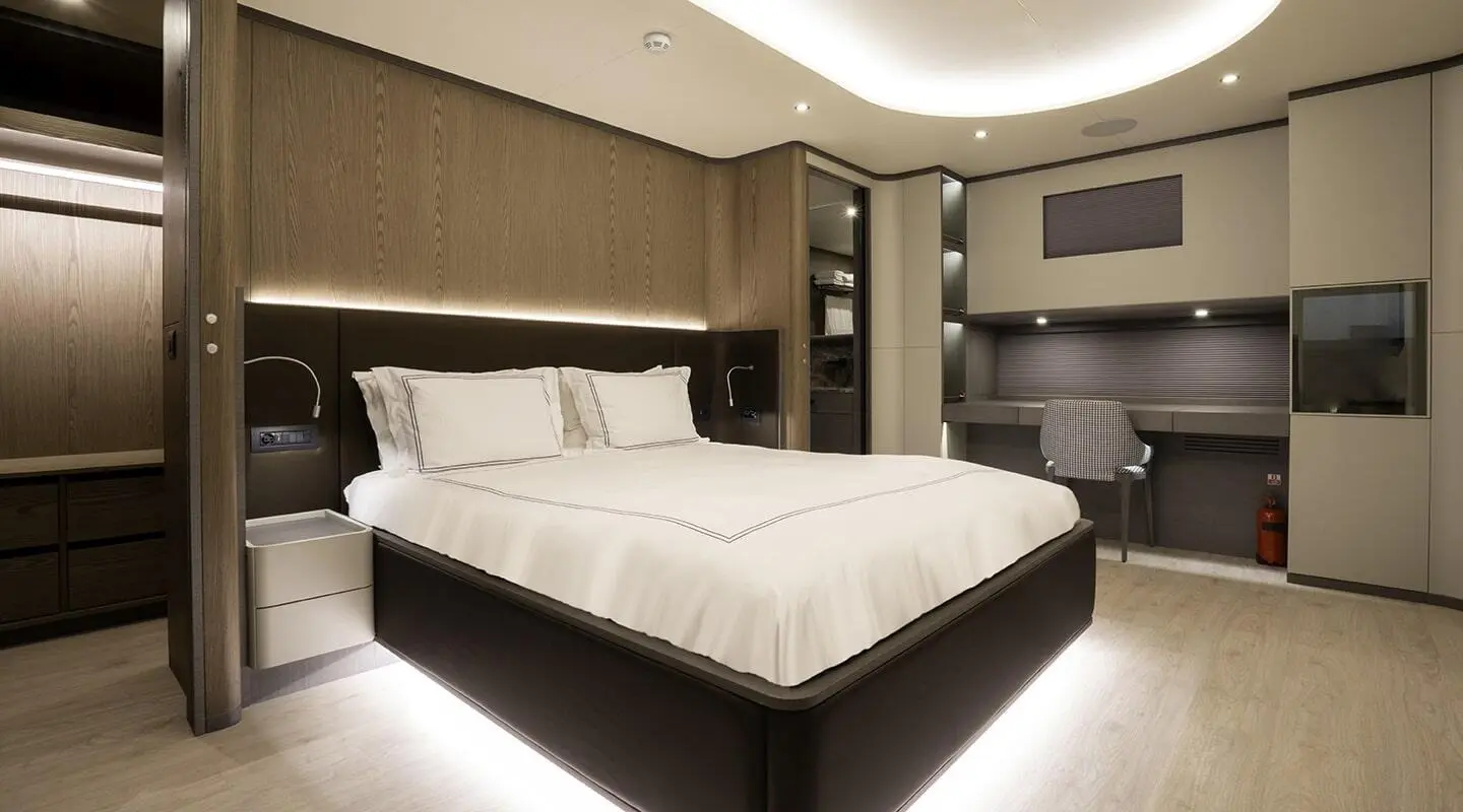 Luxurious yacht cabin with white bed, ambient lighting, and dark wood accents