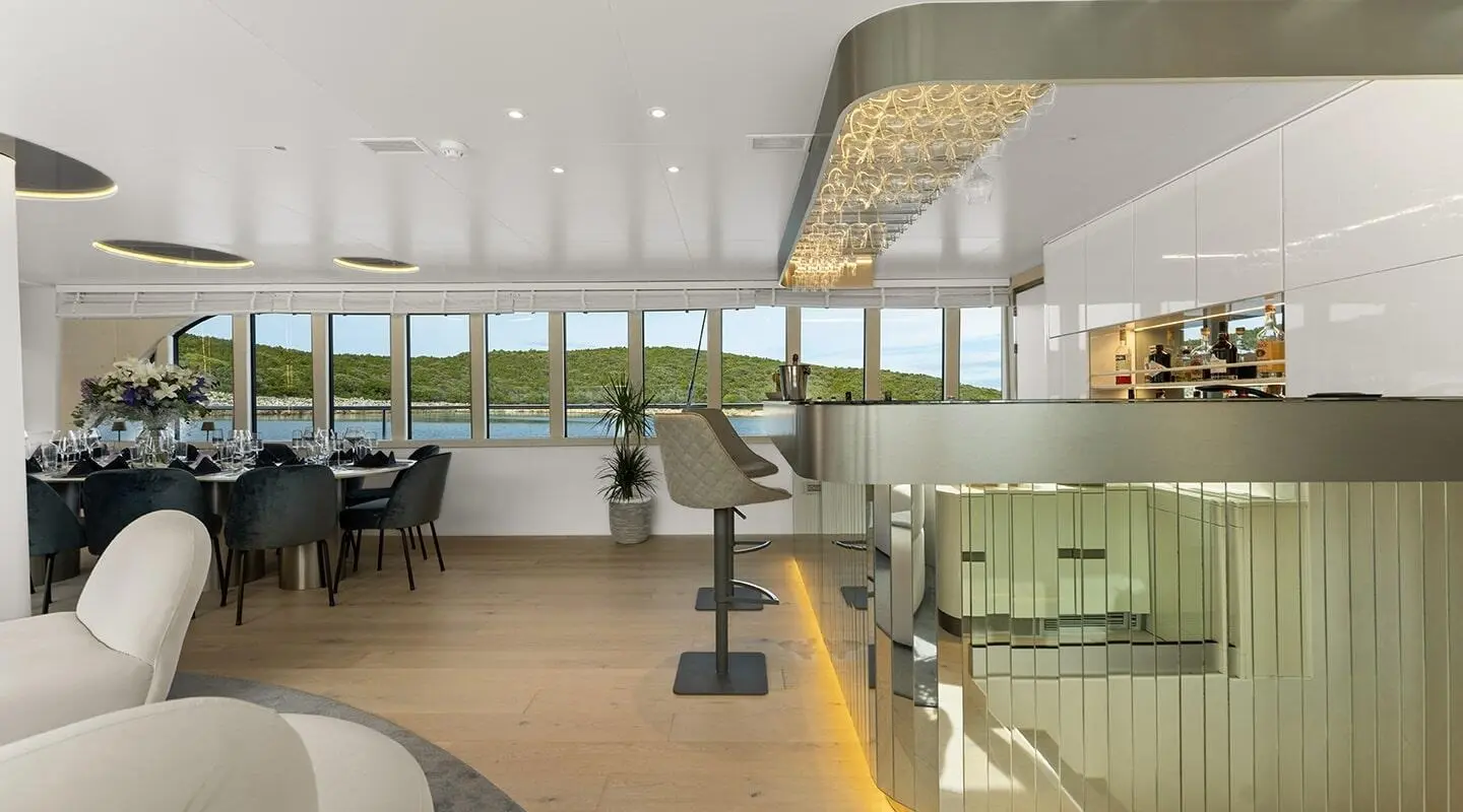 Luxurious yacht Maxita salon interior with seating, tables, and panoramic windows