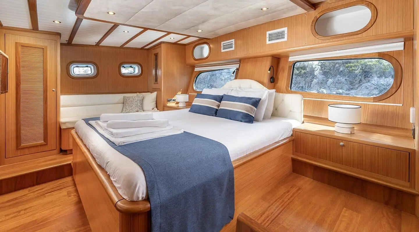 Gozdem The One yacht interior with two single beds, wooden walls, and blue bedding
